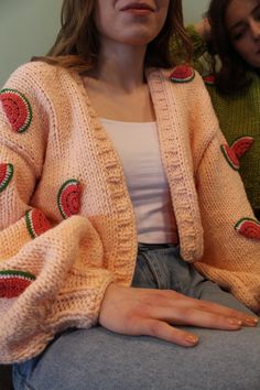 a woman sitting on a couch wearing a sweater with watermelon patches