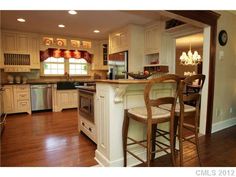 a kitchen with white cabinets and wooden floors