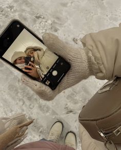 a person taking a selfie with their cell phone in the middle of two people's hands