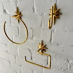 three gold stars hang on a white brick wall