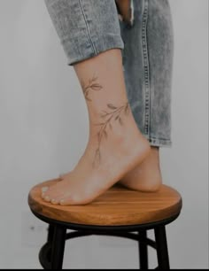 a woman's foot with a small tattoo on the side of her leg, sitting on a stool