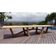 a wooden bench sitting on top of a wooden deck next to a swimming pool and trees