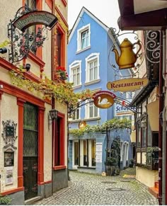 a cobblestone street in an old european town with blue buildings and red trimmings