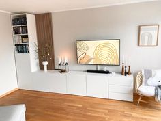 a flat screen tv sitting on top of a white entertainment center in a living room