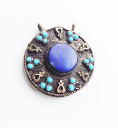 "Vintage silver alloy pendant with lapis stone and blue beads from Afghanistan. Circa 1950s. 1.5\" x 1.5\" Condition notes: vintage silver patina, missing one blue bead (see photos)." Blue Brass Jewelry For Festivals, Vintage Blue Jewelry For Festivals, Blue Medallion Necklace For Festivals, Blue Medallion Necklace For Festival, Traditional Blue Jewelry With Large Pendant, Blue Vintage Jewelry For Festivals, Traditional Blue Nickel-free Jewelry, Blue Pendant Jewelry With Silver Beads, Blue Lapis Lazuli Jewelry For Festivals