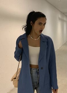 a woman standing in an empty room wearing a blue coat