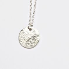 This silver moon pendant features a solid sterling silver disc that I texture with a hammer giving each one a unique pattern. The texture gives a really interesting moonscape effect with a rough stone imprint and rounded dimple pattern. It is the perfect pendant for layering with other simple jewellery for a minimal, modern look. The disc measures around 15mm diameter and the sterling silver chain comes in a choice of lengths. I textured it by hammering it on a rough stone to create irregular im Silver Moon-shaped Jewelry With Coin Pendant, Moon Shaped Sterling Silver Necklace With Coin Pendant, Sterling Silver Moon Necklace With Coin Pendant, Minimalist Etched Round Pendant Necklace, Minimalist Round Etched Necklace, Silver Moon Necklace With Coin Pendant, Silver Hammered Round Pendant Necklace, Hammered Silver Coin Necklace In Sterling Silver, Sterling Silver Necklace With Coin Pendant