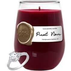 a candle with a wax stamp on it and a ring in front of the candle