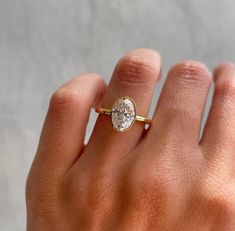 a woman's hand with a diamond ring on top of her finger, showing the center stone