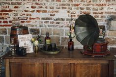 an old record player and other items sit on top of a wooden cabinet in front of a brick wall