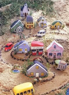 there are many small houses made out of sand and plastic cars in the middle of it