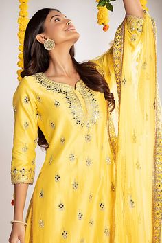 Yellow straight kurta with gota patti and mirror work. Comes with a foil work sharara and a net dupatta with fringes on the border. 
Component: 3
Pattern: Embroidered 
Type Of Work: Gota and mirror 
Neckline: Round 
Sleeve Type: Three-fourth 
Fabric: Chanderi Silk, Net
Color: Yellow
Other Details: 
Kurta with side slits
Thread and mirror work on placket
Occasion: Mehendi and Haldi, Puja - Aza Fashions Kurta Sharara Set, Kurta Sharara, Mirror Round, Silk Kurta, Straight Kurta, Sharara Set, Net Dupatta, Mirror Work, Embroidered Silk