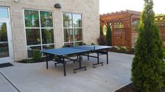 a ping pong table sitting in the middle of a patio next to a building