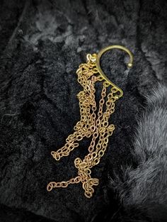 a gold chain is attached to a black velvet surface with an earring in the shape of a man's head