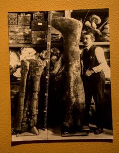 an old black and white photo of a man standing next to a large boot