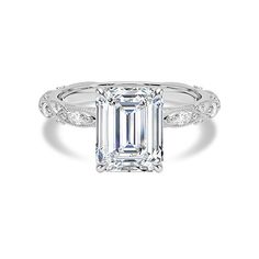 an emerald cut engagement ring with diamond accents on the band and side stones in white gold