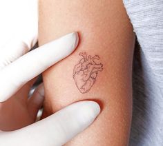 a woman's arm with a small heart tattoo on it