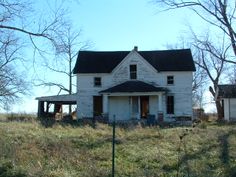 an old white house sitting on top of a lush green field