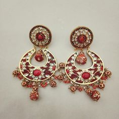 Enhance your look with these elegant Coral Chandbali Earrings. Featuring intricate designs with coral drops, these earrings bring a perfect blend of tradition and sophistication to any outfit. Ideal for festive occasions, they add a vibrant and graceful touch to your ensemble. Length: 3" to 3.5" Material: 24Kt gold foil, lac Stones: Kundans, semi precious corals, semi precious pearls Elegant Red Chandbali Danglers, Traditional Chandelier Earrings With Dangling Beads, Red Chandbalis For Celebration, Party Temple Jewelry Earrings With Dangling Beads, Celebration Chandbalis With Dangling Beads, Elegant Handmade Festive Chandbalis, Elegant Chandbali Beaded Earrings With Latkans, Traditional Dangling Beads Earrings For Celebration, Elegant Chandbali Beaded Earrings For Festivals