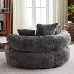 a large grey round couch sitting on top of a white rug in a living room