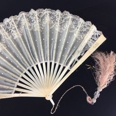 an old white lace fan next to a string