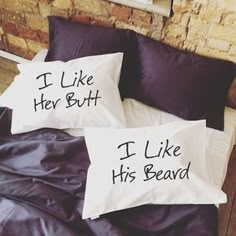 two pillows that are sitting on top of a bed with black sheets and pillow cases