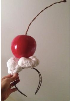 a person holding an object made out of marshmallows, cherries and whipped cream