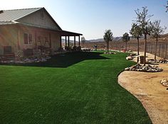 a house in the middle of a field with rocks and grass on the ground next to it