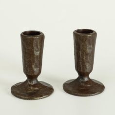 two metal candlesticks sitting next to each other