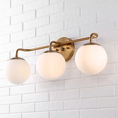 three lights are on the wall in front of a white brick wall