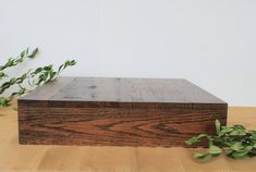 a wooden box sitting on top of a table next to some green leaves and plants