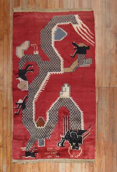 a red rug with an animal and people on it in the middle of a wooden floor