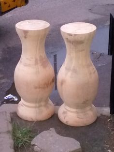 two large white vases sitting next to each other on the ground in front of a yellow truck