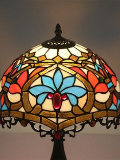 a stained glass lamp on a table with a black base and red, blue, yellow, orange, and white flower design