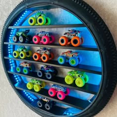 there are many toy cars on display in the wall behind the tire rims that is lit up