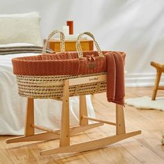 a wooden rocking chair with an orange blanket on it's back, in front of a bed