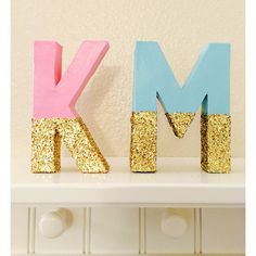 the letters k and m are painted pink, blue and gold with glitter on them