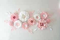 pink and white paper flowers are arranged on the wall