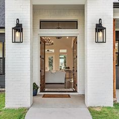 the front entrance to a house with two lights on each side and a couch in the doorway