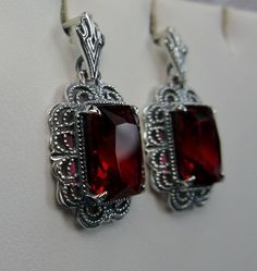 Simulated Red Ruby Solid Sterling Silver Earrings Short Festoon Design#E8z (shorter version) These Victorian reproduction estate earrings are solid sterling silver. These filigree earrings have stunning simulated red ruby gemstones. Each stunning gem is 10mm x 8mm x 5mm in dimension. The earrings are approximately 1/2" x 1" (13mm x 23mm). The unique earrings are marked 925 for solid sterling silver. These lovely earrings were refashioned from an antique Victorian cameo necklace. Quintessentially Red Jewelry Set, Jeweled Flowers, Armenian Jewelry, Pendant And Earring Set, Red Stone Ring, Marcasite Jewelry, Antique Filigree, Filigree Jewelry, Mid Century Jewelry