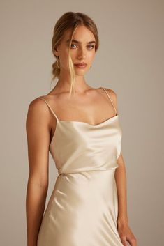 a woman wearing a dress with straps and a low neckline is posing for the camera