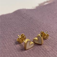 The Sweetheart Studs Earrings Feature White Enamel With Gold Detailing. Elegant White Open Heart Earrings, White Heart Charm Earrings, White Heart Charm Earrings For Valentine's Day, White Dainty Earrings With Heart Charm, White Dainty Heart Earrings For Pierced Ears, Dainty White Heart Earrings For Pierced Ears, Valentine's Day White Heart Charm Earrings, White Earrings With Heart Charm As Gift, White Heart-shaped Earrings With Heart Charm