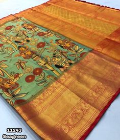 an orange and green saree with floral designs on the border, sitting on a white surface