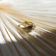 a ring sitting on top of a wooden table next to a white sheet with light coming through it