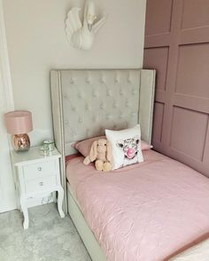 a bedroom with a pink bed and white nightstands