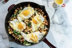 three eggs are in a skillet on the counter next to a cup of tea