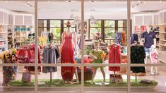 a store window with mannequins and dresses on display