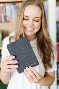 a woman holding up a book in front of her face and smiling at the camera