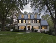 a large white house sitting on top of a lush green field next to tall trees