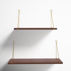 two wooden shelves with gold metal handles against a white wall, one is empty and the other has no shelf